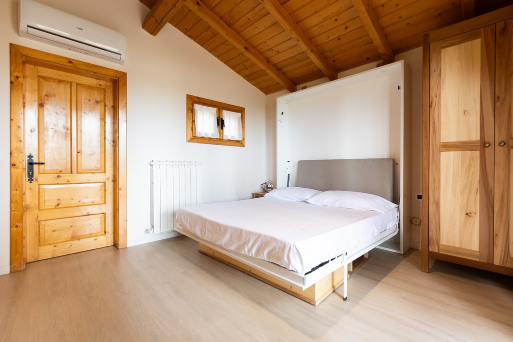 Camera di uno chalet con letto matrimoniale e soffitto in travi di legno