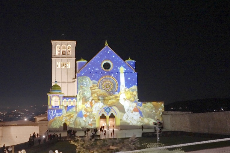 La Basilica di San Francesco di notte con le proiezioni natalizie sulla facciata e le luci della valle