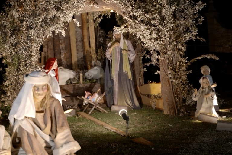 Le statue del presepe sotto una capanna di rami, illuminate di notte ad Assisi