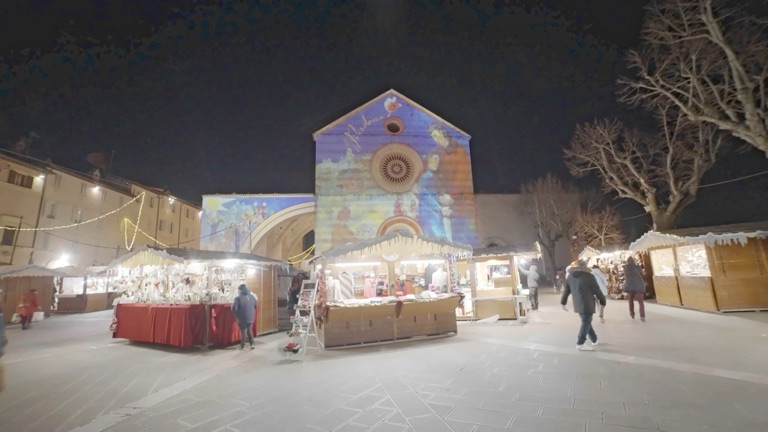 Le casette dei mercatini di Natale davanti alla Basilica di Santa Chiara, ad Assisi, di sera